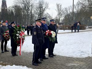 na zdjęciu zgromadzone przed pomnikiem osoby, w tym mundurowi z wieńcami