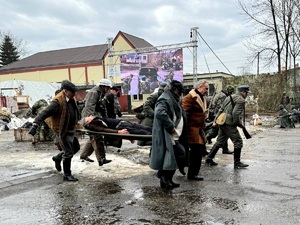 na zdjęciu żołnierze i przebrane osoby w trakcie widowiska historycznego, niosą osobę na noszach