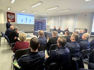 na zdjęciu policjanci i zgromadzone osoby siedzące w sali na krzesłach