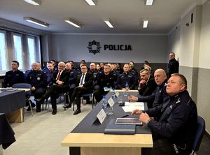 na zdjęciu policjanci i zgromadzone osoby siedzące w sali na krzesłach
