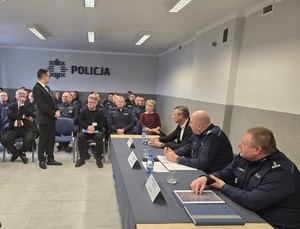 na zdjęciu policjanci i zgromadzone osoby siedzące w sali na krzesłach