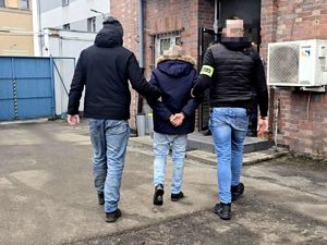 na zdjęciu dwóch nieumundurowanych policjantów prowadzi zatrzymanego mężczyznę