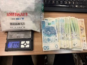 na zdjęciu biały proszek w worku na wadze, obok banknoty pięćdziesięcio stu i dwustuzłotowe