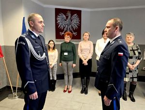 na zdjęciu widźmy dwóch policjantów ustawionych naprzeciwko siebie , za nimi stojący w rzędzie pracownicy cywilni