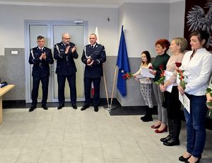 na zdjęciu stojący w rzędzie pracownicy cywilni obok nich trzej policjanci bijący brawo