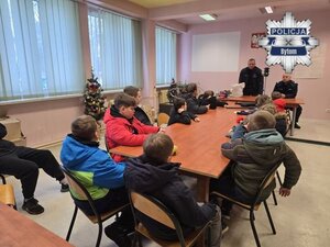 na zdjęciu uczniowie siedzący w sali i dwaj mundurowi