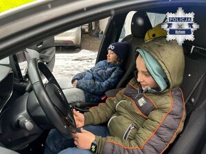 na zdjęciu dwójka dzieci siedzących w radiowozie