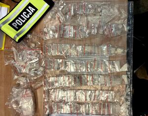 ponad sto sztuk woreczków strunowych z sypką substancją białego koloru ułożonych na stole