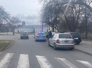 policjanci przy radiowozie służbowym obok radiowozów służbowych, obok samochód osobowy