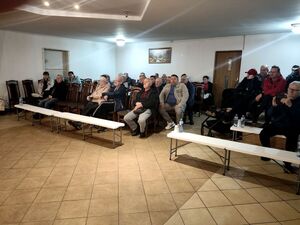 seniorzy siedzący na krzesłach w sali