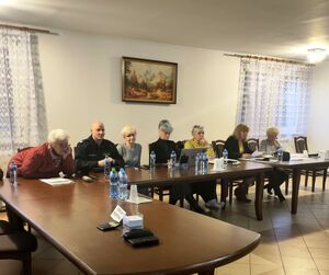 policjant i seniorzy siedzący w sali przy stole