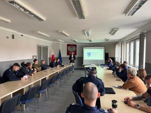 policjanci siedzący na sali, przed nimi mężczyzna i wyświetlony slajd