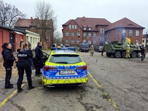 pojazd militarny, policjanci i radiowozy policyjne