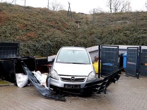 samochód osobowy srebrnego koloru, przy skarpie, przed nim uszkodzone przęsło ogrodzenia