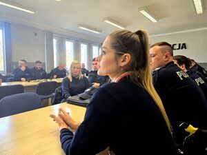 policjantki i policjanci siedzący przy stołach w sali
