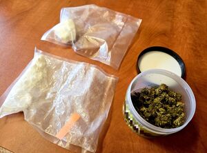 leżące na stole woreczki strunowe z białą sypką substancją i susz roślinny w okrągłym pudełku