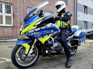 policjant siedzący na motocyklu służbowym, wido z boku