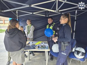 policjant, policjantka i harcerze przy stoisku profilaktycznym