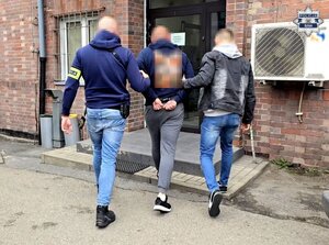 dwóch nieumundurowanych policjantów wprowadza zatrzymanego mężczyznę do bytomskiej komendy
