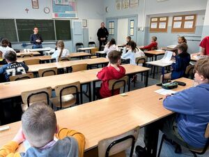 uczniowie siedzący w sali przy ławkach