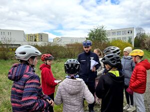 policjant ruchu drogowego i uczniowie w kaskach na głowach
