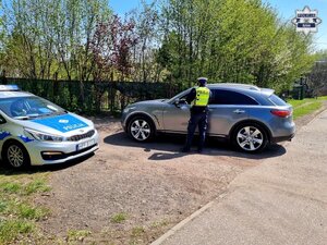 policjant przy drodze przy samochodzie osobowym obok radiowóz służbowy