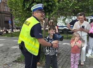 policjant drogówki z ręcznym miernikiem prędkości obok niego dzieci