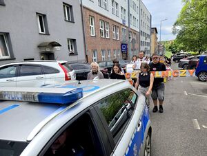 tył radiowozu za którym idą uczestnicy wydarzenia