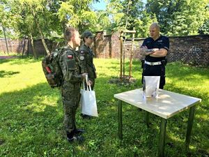dwóch chłopców w strojach moro i policjant podczas konkurencji z pierwszej pomocy