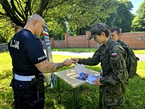 dwóch policjantów i dwóch chłopców w strojach moro, policjant przekazuje znaczek chłopcu