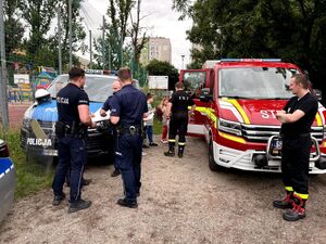 policjanci i strażacy przy radiowozach służbowych