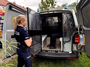 policjantka obok radiowozu, w radiowozie dziewczyna