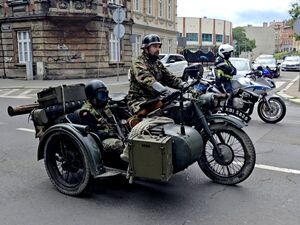 motocykl militarny za nim policjant i motocykl służbowy