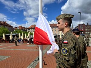 młody żołnierz trzyma flagę polski przymocowaną do masztu