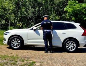 policjant stojący przy samochodzie białego koloru