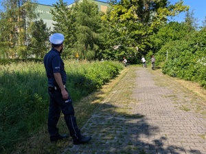 policjant ruchu drogowego obserwuje dzieci jadące na rowerach