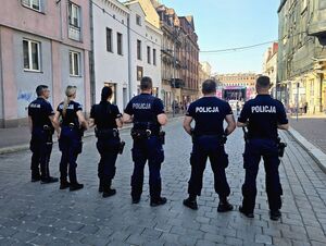 dwie policjantki i czterech policjantów, ustawieni w rzędzie, stoją tyłem