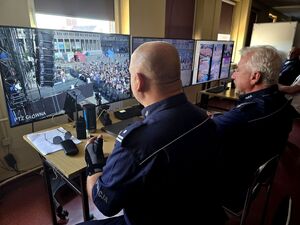 dwóch policjantów przed monitorami na których widoczni są uczestnicy wydarzenia
