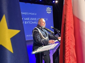 bytomski komendant przemawia przy mównicy obok niego flagi Polski i Unii Europejskiej