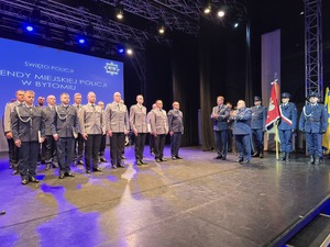 policjanci na scenie ustawieni w rzędach, obok komendanci i poczet sztandarowy