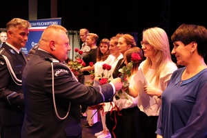 wojewódzki komendant i bytomski komendant wręczają kwiaty i gratulacje kobietom na scenie - pracownikom cywilnym