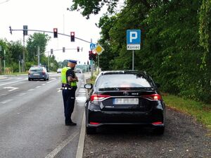 policjant w trakcie kontroli pojazdu, stoi przy oknie kierowcy pojazdu czarnego koloru