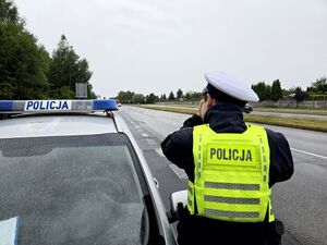 policjant przy radiowozie, wykonuje pomiar prędkości