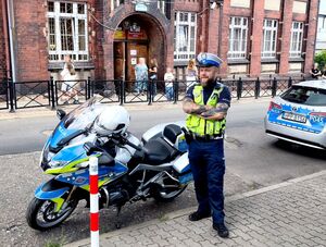 policjant przy motocyklu służbowym stojący przed szkołą