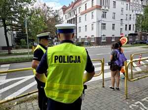 widzimy dwóch policjantów ruchu drogowego stojących przy szkolnym przejściu dla pieszych