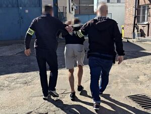 dwóch nieumundurowanych policjantów prowadzi zatrzymanego mężczyznę
