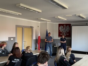 licealiści siedzący w sali przed nimi policjant i policjantka